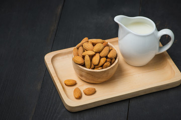 Almond milk in glass with almonds on  black wooden table
