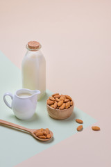 Almonds and milk bottle on light background. Almond nuts in spoon.