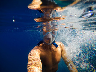 Young male explorer in snorkeling adventure. Selfie shot underwater in the middle of the sea.