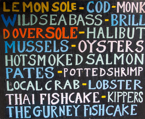 A fishmonger's sign listing the various different types of fresh fish and seafood available to buy.