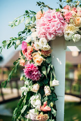 open air decorated area for the wedding ceremony with a wooden arch decorated with pink and white flowers