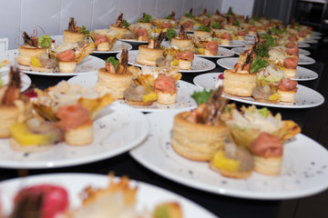 Many plates of appetizers being prepared in commercial kitchen, for an event