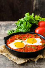 Mexican breakfast: Huevos rancheros in iron frying pan on wooden table