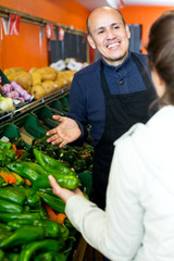 Friendly worker selling vegetables to female customer