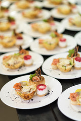 Many plates of appetizers being prepared in commercial kitchen, for an event