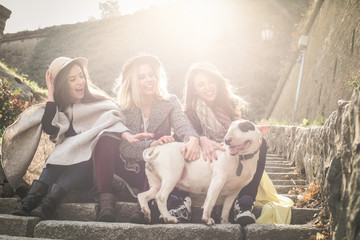 Three best friends sitting on the stairs. Young girls with their pets.
