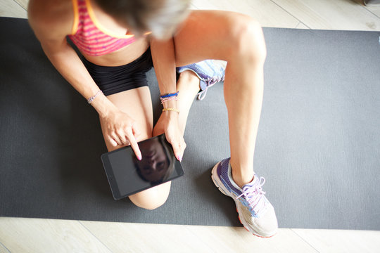 Ragazza con abbigliamento sportivo cerca esercizi su tablet a casa