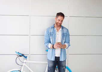 Casual guy next to a vintage bicycle with the mobile