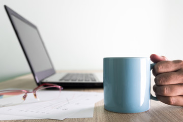 Coffee break. Businessman drinking coffee on office table with glasses and business report background.