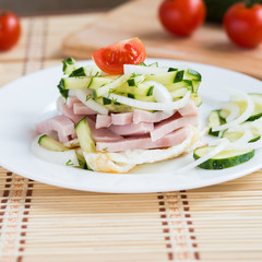 Breakfast. Salad with fried eggs, ham, cucumber, onion, tomatoes