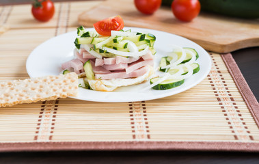 Breakfast. Salad with fried eggs, ham, cucumber, onion, tomatoes
