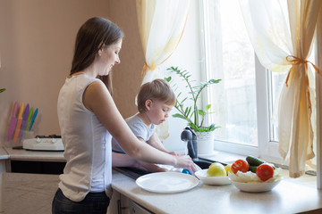 Obraz na płótnie Canvas kitchen mom son wash fruits and vegetables