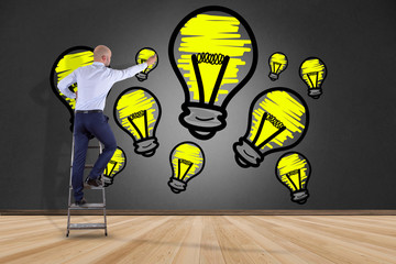 Businessman in front of a wall drawing a bulb lamp idea - Creative concept