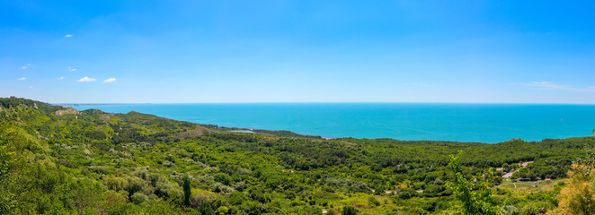 Panoramic sea view from altitude on the hill with green trees at the sunny summer day