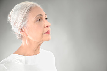 Beautiful elegant elderly woman on gray background