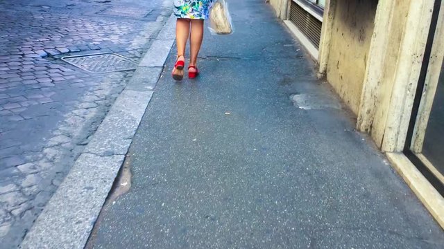 Una donna con i tacchi rossi cammina sulla strada