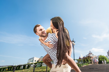 Happy young multiethnic couple piggybacking and smiling each other in city