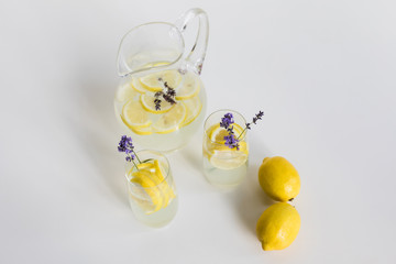 high angle view of fresh homemade drinks with lemon pieces and lavender flowers in glasses isolated on white