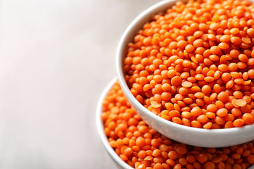 Bowls with red lentils on light background