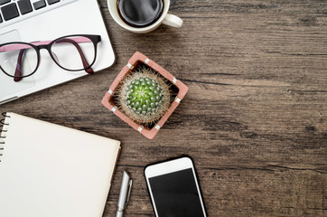Brown wood office desk table with a book, pen, cactus and phone for working.