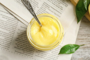 Glass jar with delicious lemon curd on table
