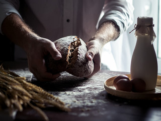 Man bakes fresh bread on kitchen table 