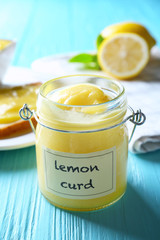 Glass jar with delicious lemon curd on wooden table