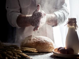 Door stickers Bread Man sprinkling flour over freshly baked bread on kitchen table