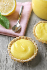 Tasty cookies with lemon curd on wooden table