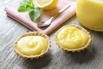 Tasty cookies with lemon curd on wooden table