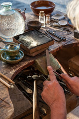 Goldsmith working on his bench, using a file