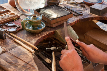 Goldsmith working on his bench, using a file