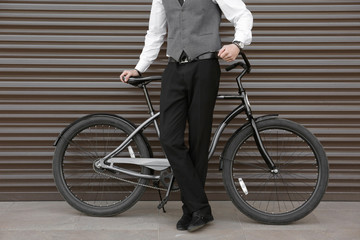 Fototapeta premium Young man with bicycle on color wall background