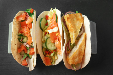 Stand with tasty fish tacos on dark table