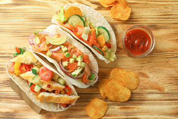 Stand with tasty fish tacos on wooden background