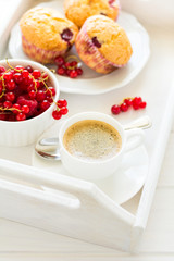 Traditional breakfast: espresso, fruit muffins and ripe berries on white wooden salver. Selective focus