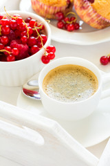 Traditional breakfast: espresso, fruit muffins and ripe berries on white wooden salver. Selective focus