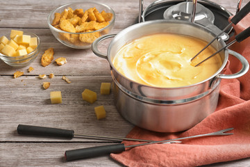 Delicious cheese fondue with rusks on table