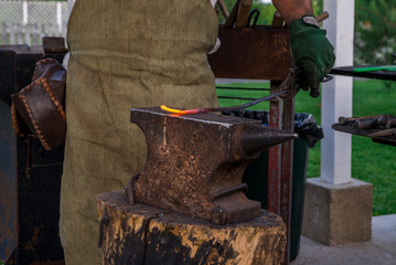 The smith holds a metal bar heated to melting on the anvil, before hammering. Retro work., Craft....