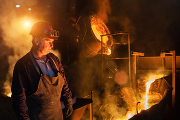 Foundry worker looking at falling in molten steel.