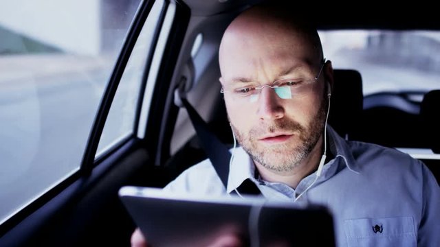 Bald Businessman in the Car Having a Skype Call