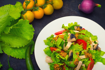 Fresh salad with chicken, mushrooms, lettuce, tomato and mustard dip. Dark stone background. Top view. Close-up