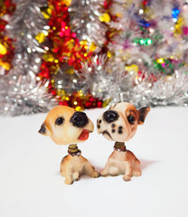 Two cute little toy dogs waiting for Christmas on the background of Christmas decoration