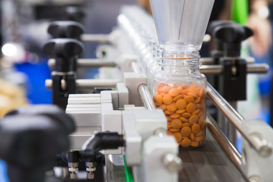 pharmaceutical industry, medicine pills are filling in the plastic bottle on production line machine conveyor at the medical factory. selective focus.