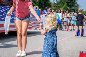 handing candy to little girl at hometown 4th of July parade