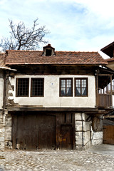 Old house stone paved road alley, wooden benches Bansko ski tourist centre of Bulgaria