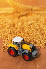 Obraz premium Agricultural tractor toy and harvested wheat