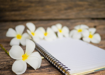 Frangipani flower with notebook on wooden table