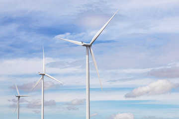 Fototapeta premium white wind turbines generating electricity in wind power station under blue sky background 