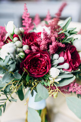beautiful wedding bouquet with white, red and purple flowers standing on a white chair